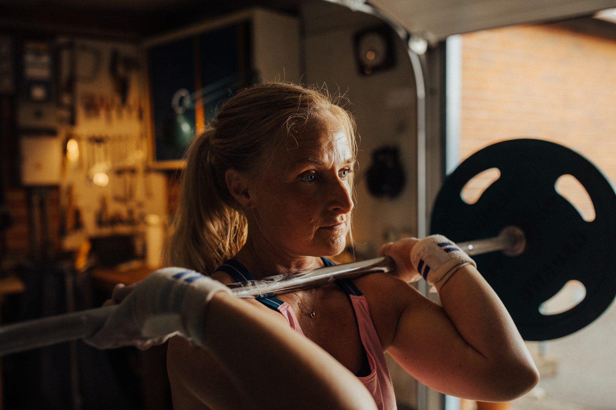 A woman lifting a barbell in a home garage gym